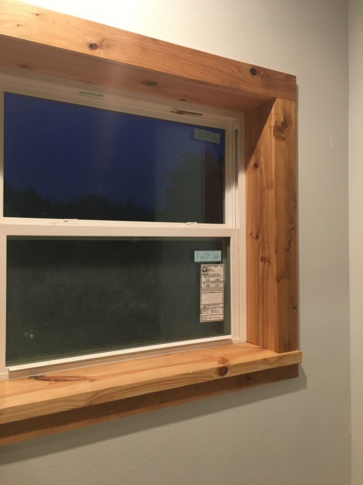 an empty window in the corner of a room with wood framing and white trim on the windowsill