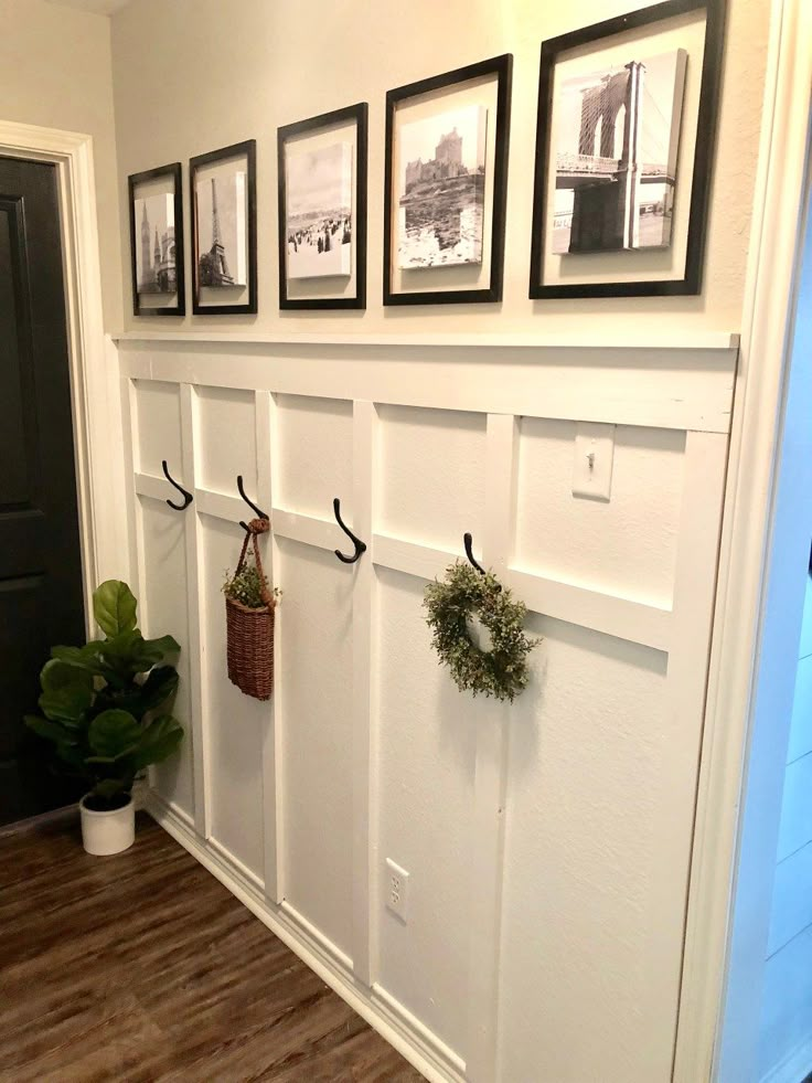 the entryway is decorated with white paneling and pictures on the wall above it