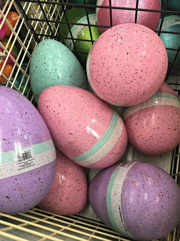 a basket filled with lots of pink and purple eggs on top of a shelf next to each other