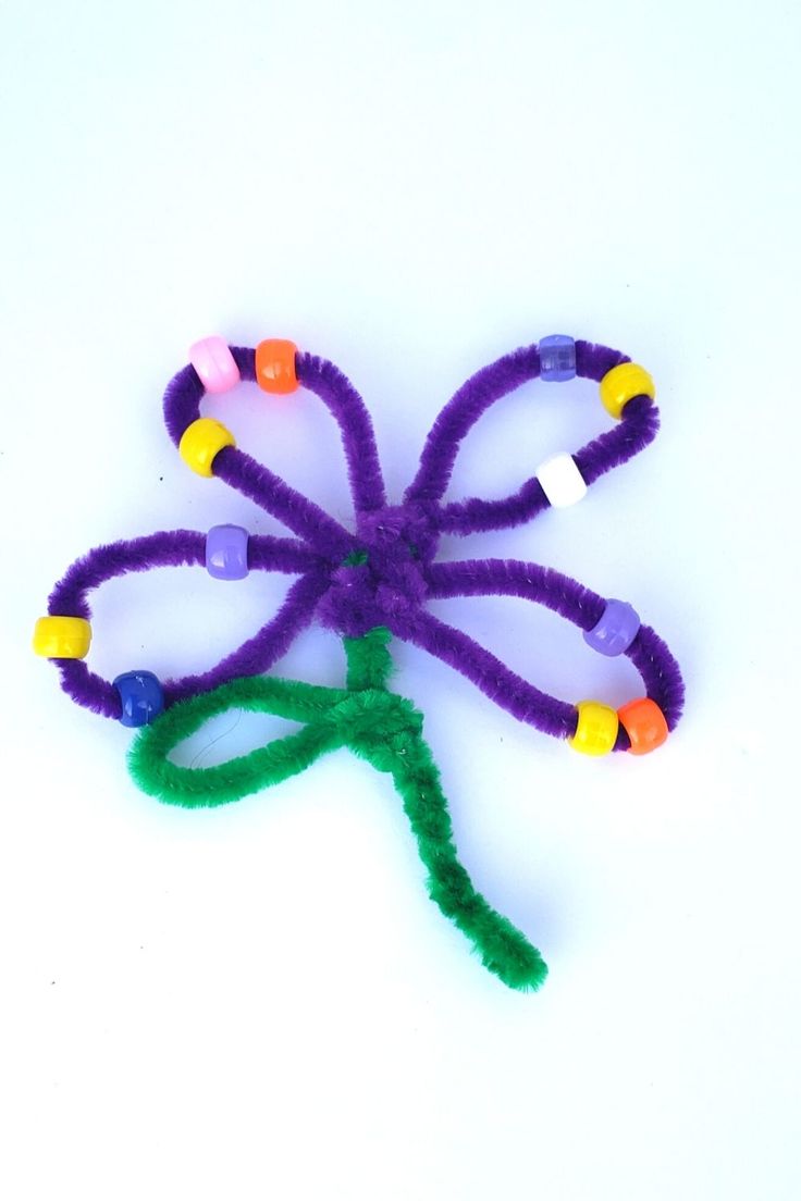 a purple flower made out of beads on a white surface