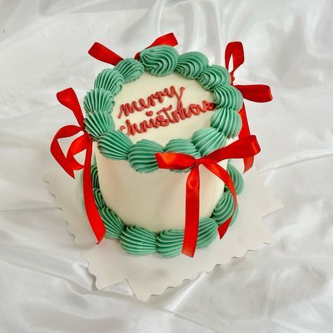 a white cake with green icing and red ribbon around it