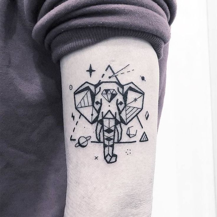 an elephant tattoo on the left inner forearm and upper arm, with geometric shapes in black ink