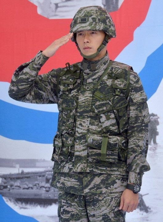 a soldier saluting while standing in front of a wall