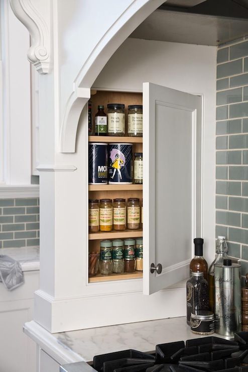 an open cabinet in the middle of a kitchen with spices and condiments on it