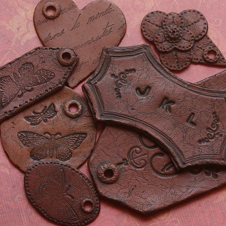 several different types of leather tags on a pink cloth background with butterflies and flowers in the middle