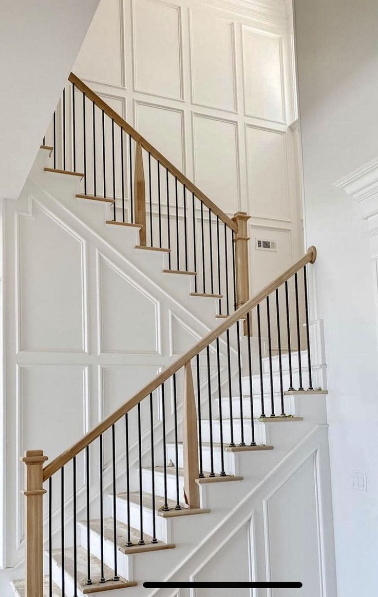 a white staircase with wooden handrails and black railing on the top floor in an empty room