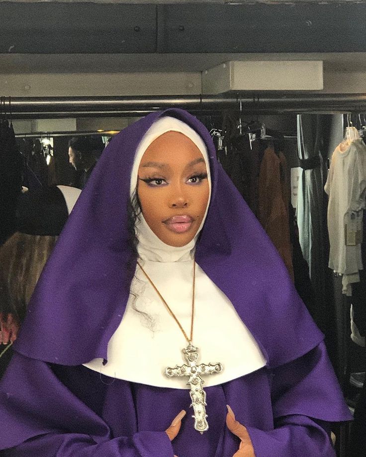 a woman wearing a purple nun outfit and holding a cross