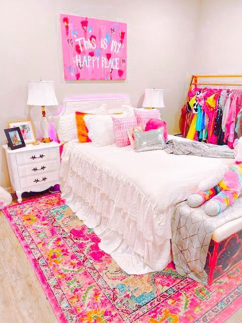 a bedroom with pink and white decor on the walls, rugs, and bedding