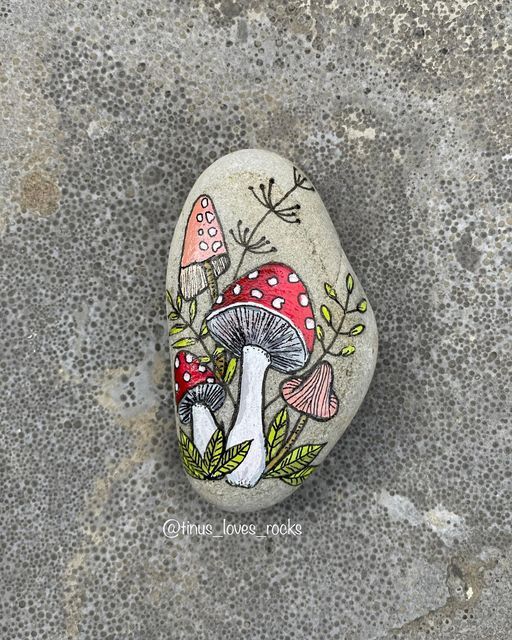 a painted rock with mushrooms and leaves on it