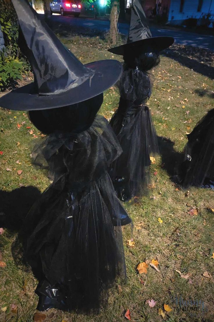 two black witches are sitting in the grass