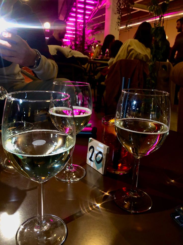 three wine glasses sitting on top of a table next to each other in front of people