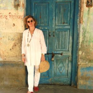 a woman standing in front of a blue door with a hat on her head and sunglasses on