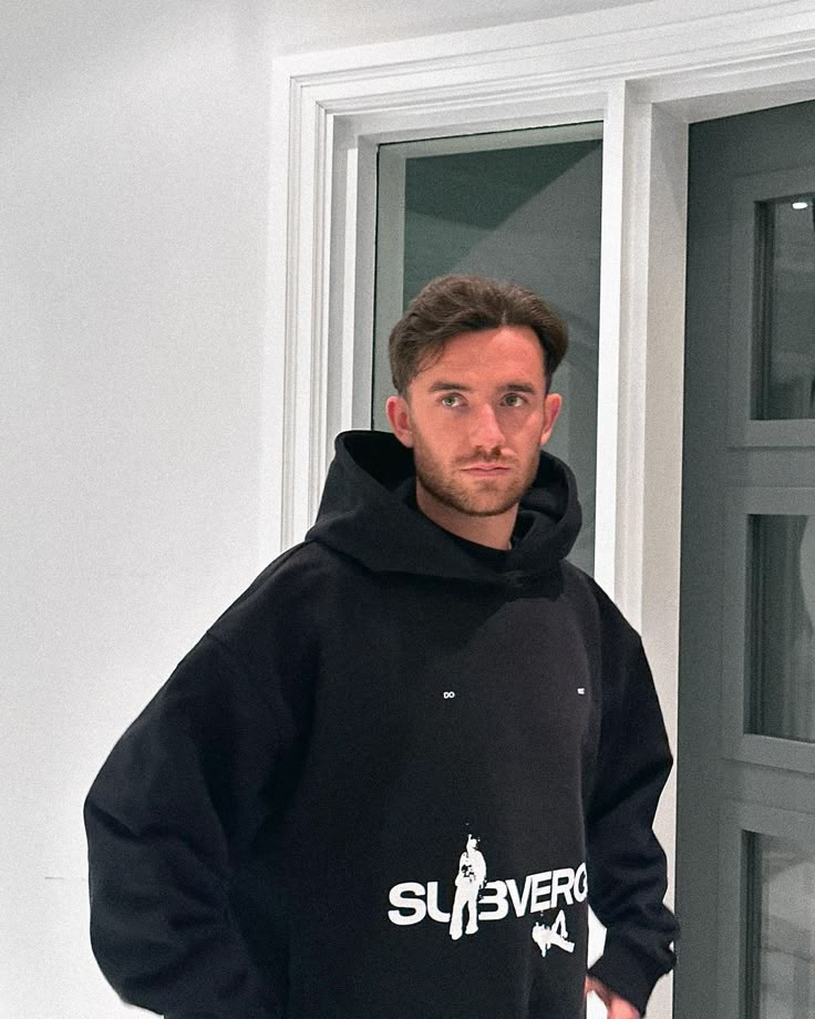 a man standing in front of a door wearing a black hoodie