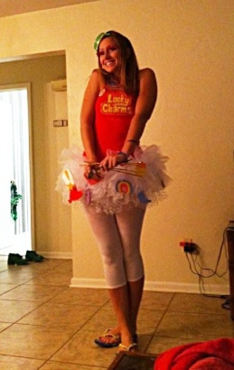 a woman in a red shirt and white tutu is standing on the floor with her legs crossed