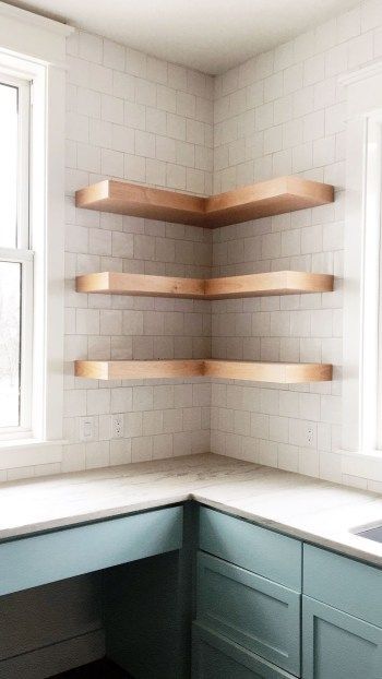 a corner kitchen with white tile and wooden shelves