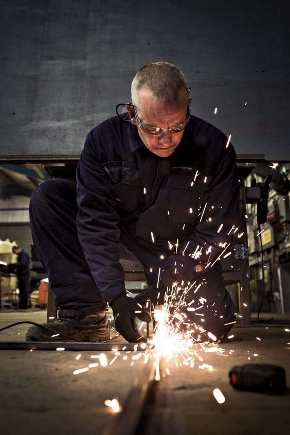 a man is working on some kind of thing with sparks in his hands and looking down at the floor