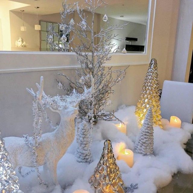 christmas decorations are displayed in front of a mirror with candles on the side and snow around them