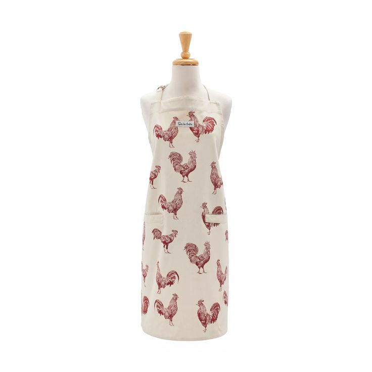 a white dress with red roosters on it and a wooden mannequin head