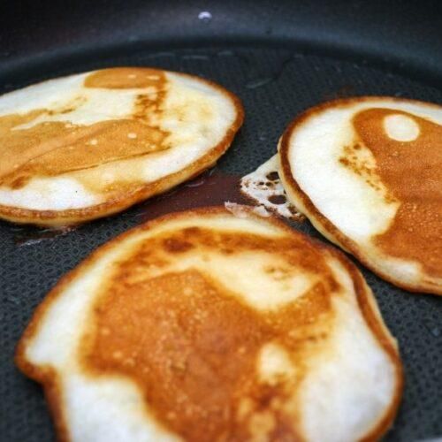 three pancakes that have been cooked in a skillet with syrup on them and are being fried