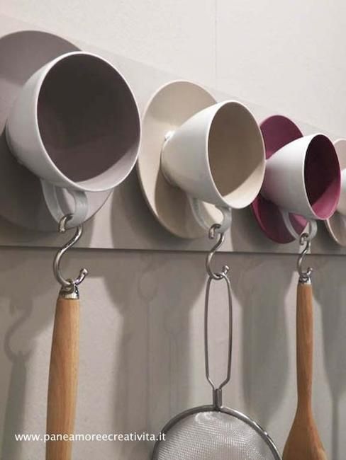 five cups hanging on the wall with spoons and spatulas attached to them