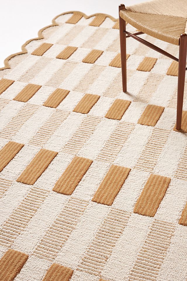 a chair sitting on top of a white rug next to a wooden chair and table