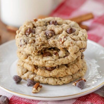 two cookies stacked on top of each other with chocolate chips and pecans in the background