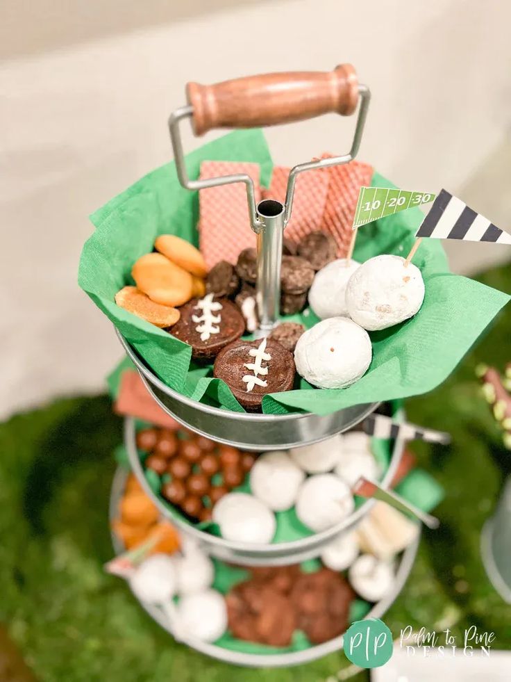 a three tiered tray filled with different types of snacks and candies on top of green grass