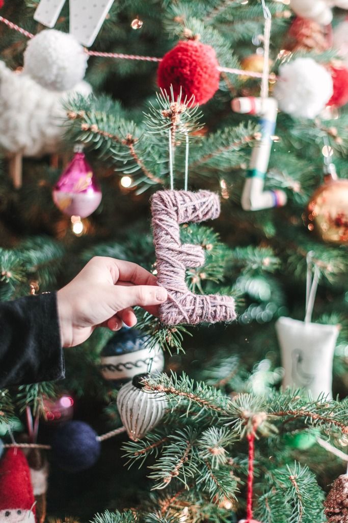 a hand holding a rope ornament in front of a christmas tree with ornaments