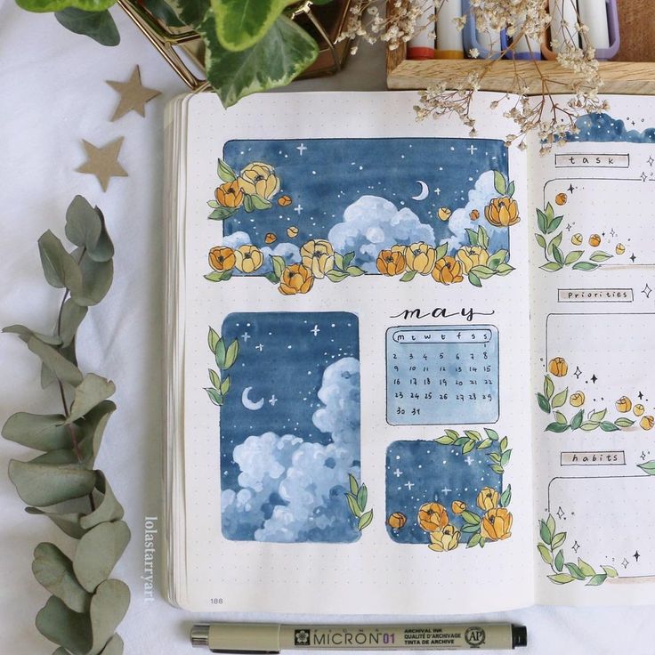 an open planner book sitting on top of a table next to a plant and pen