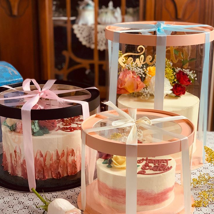 three tiered cakes with ribbons and bows sit on a table next to each other