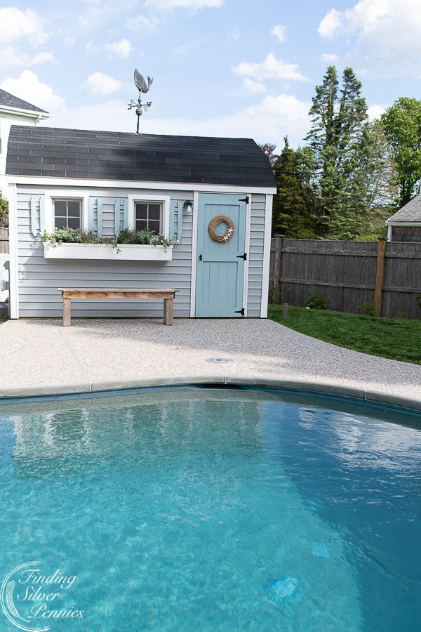 a small pool with a bench next to it and a shed in the back ground