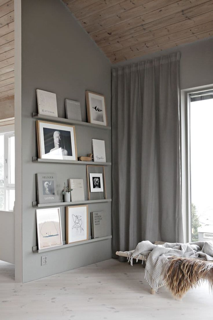 a living room with gray walls and pictures on the wall, along with framed photographs