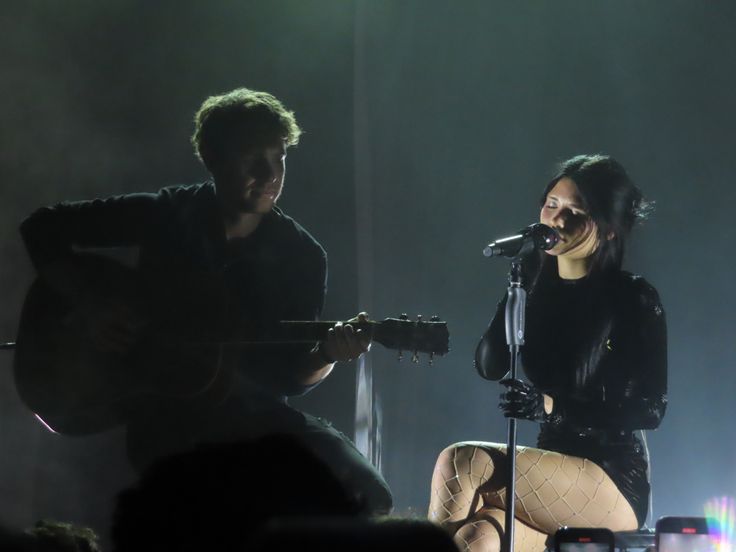 two people on stage playing instruments and singing