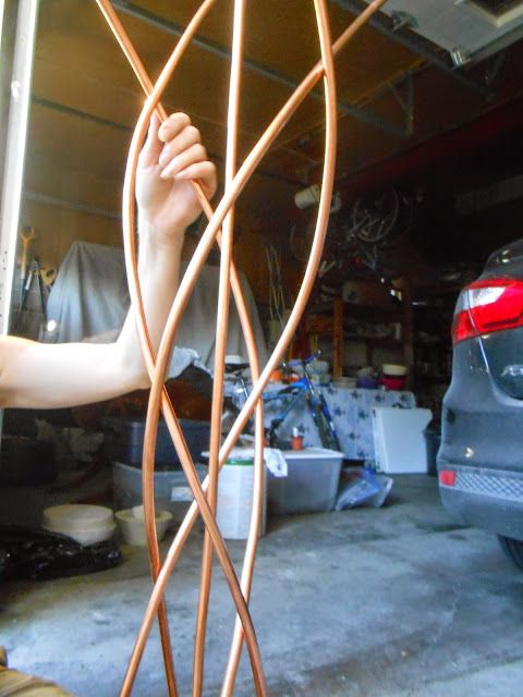 a man is working on a piece of wood in a garage with his car parked behind him