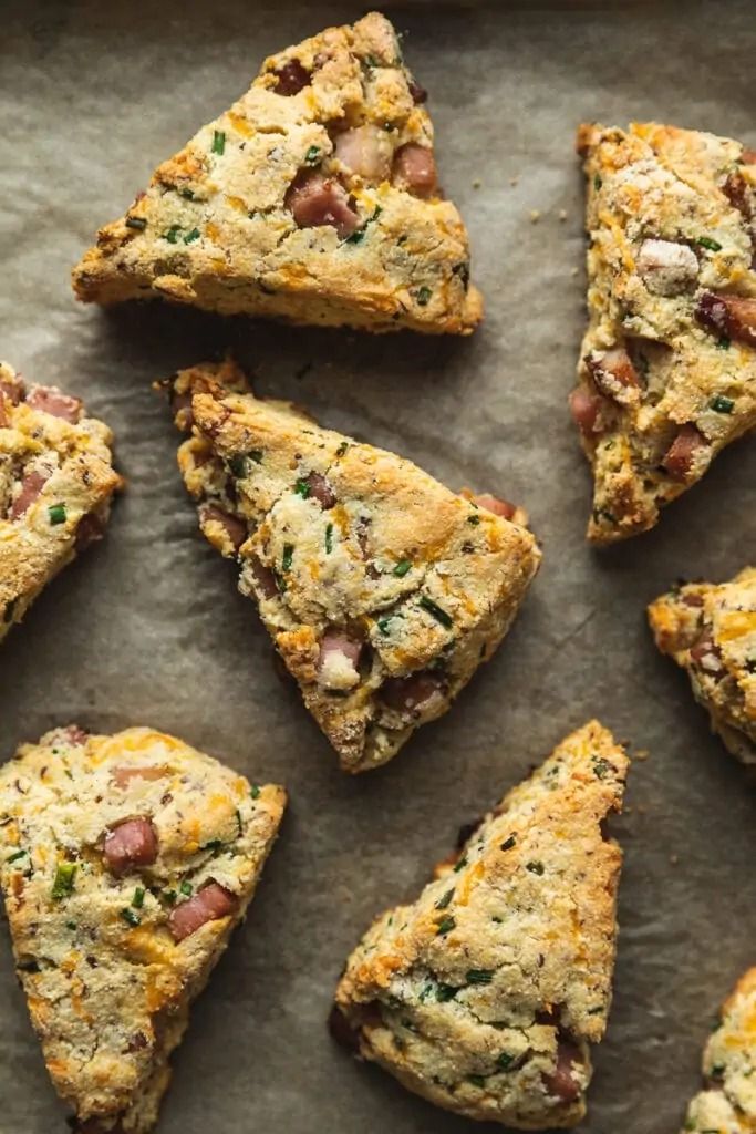 several pieces of food are arranged on a sheet of baking paper, including scones