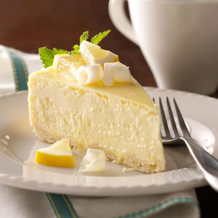 a piece of cheesecake on a plate with a fork and cup in the background