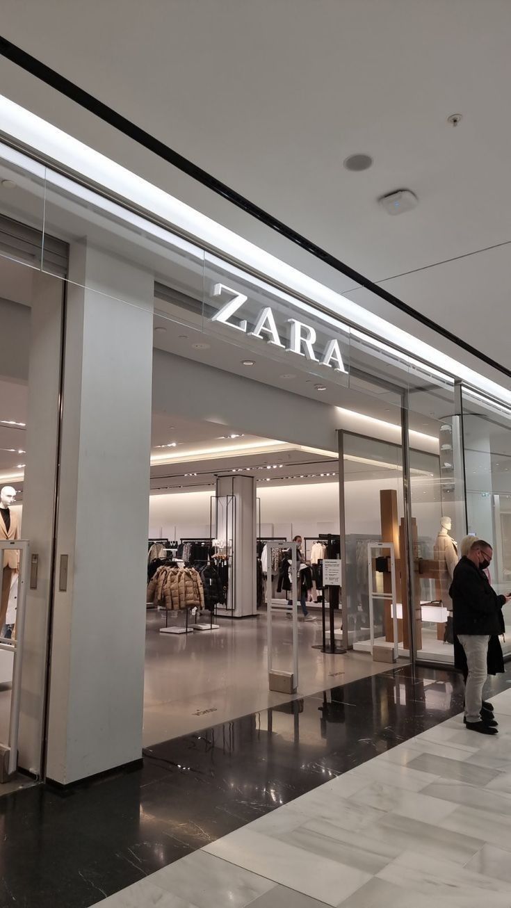 people are walking in front of a store with glass doors that says zara on it