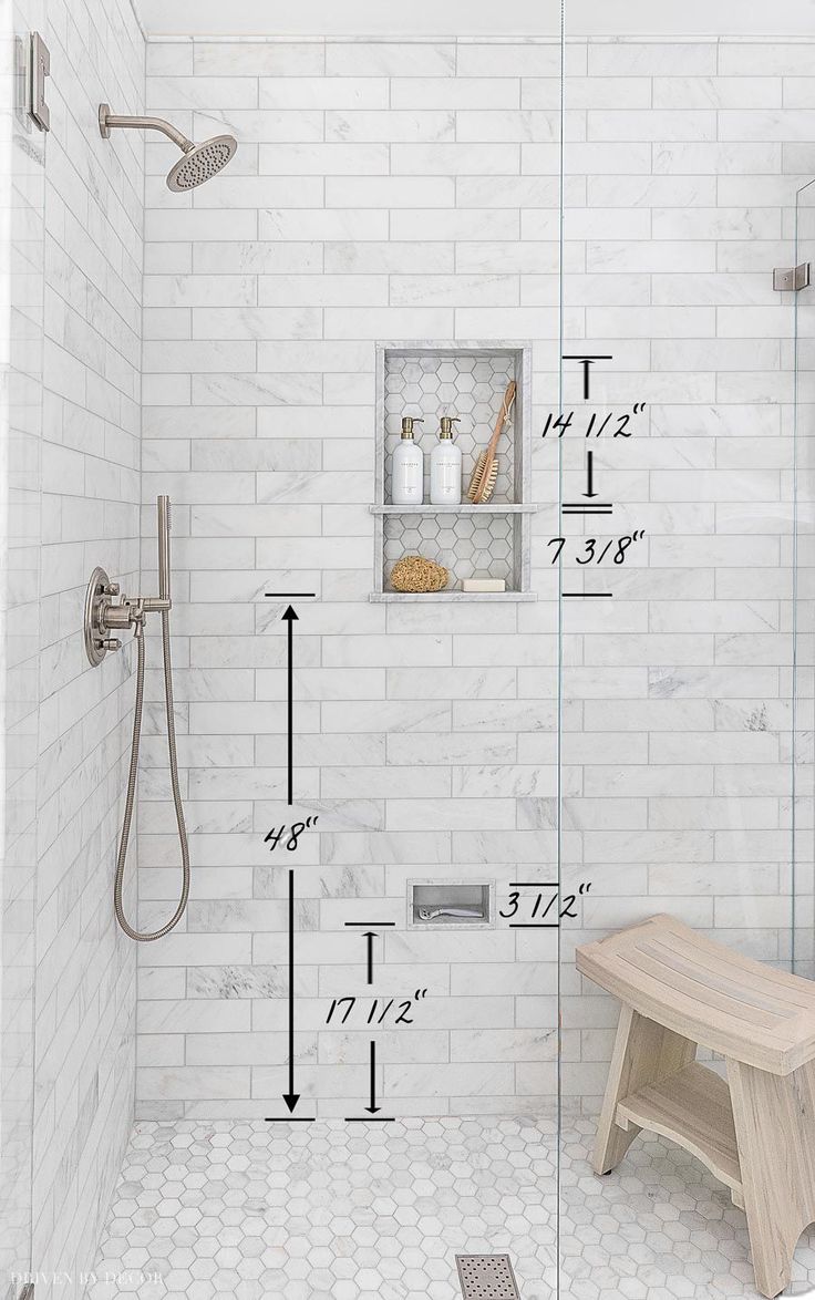 a bathroom with a bench, shower head and white brick wall in the shower area