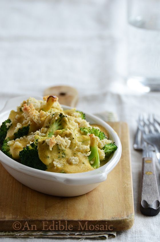 broccoli and noodles in a white bowl on a cutting board with utensils