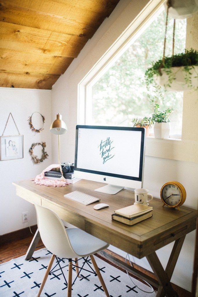 a desk with a computer on it in front of a window