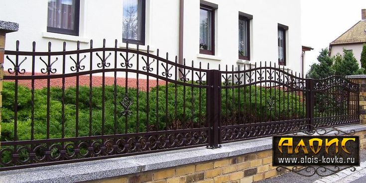 an iron fence is next to a brick wall