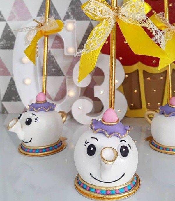 three white teapots with yellow bows on them and one has a pink nose