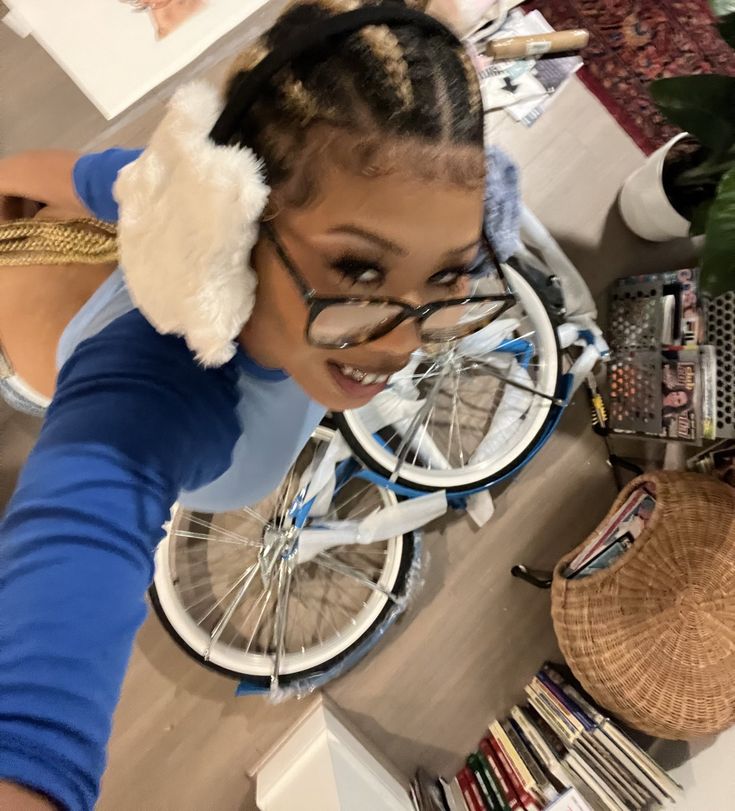 a girl with glasses and a stuffed animal on her head standing next to a bicycle