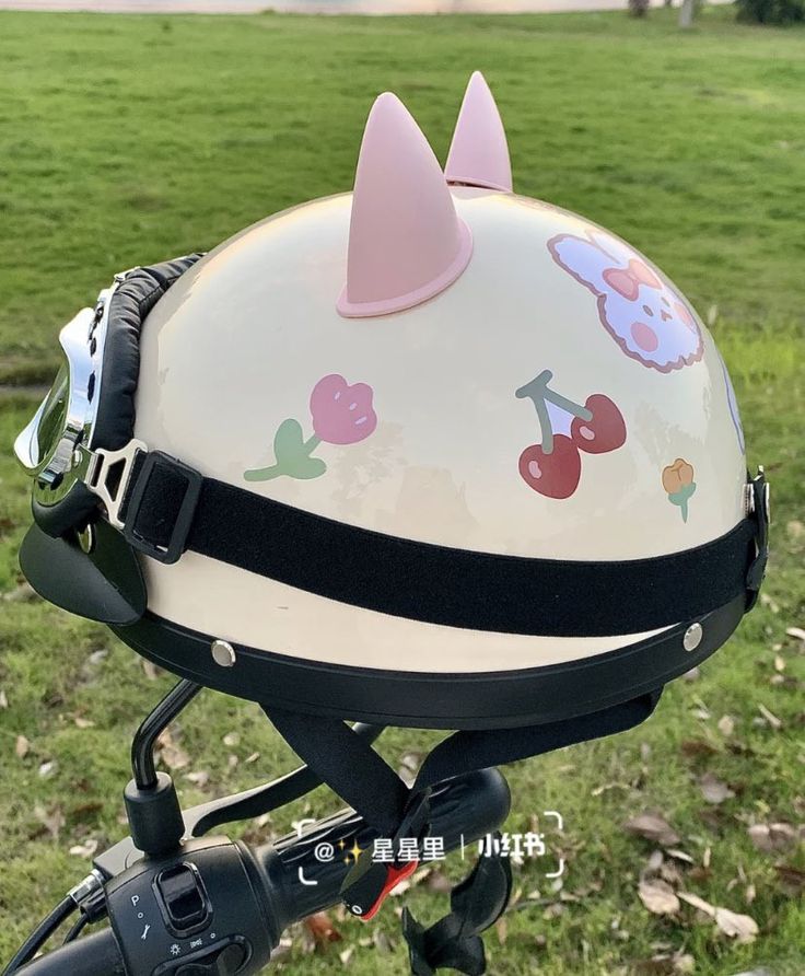 a close up of a helmet on the back of a bike in a field with trees and grass