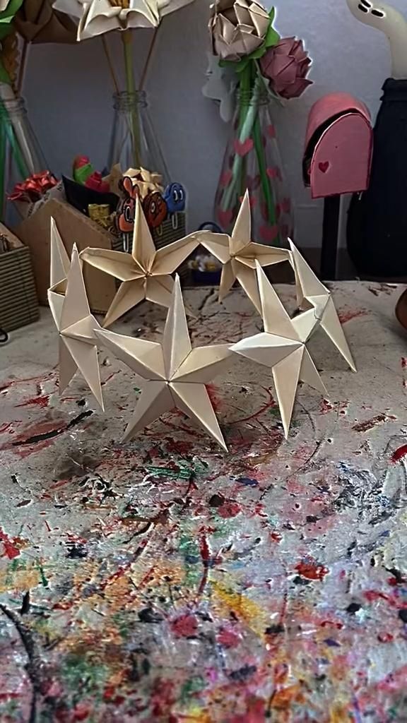 two origami stars sitting on top of a table covered in paint and paper