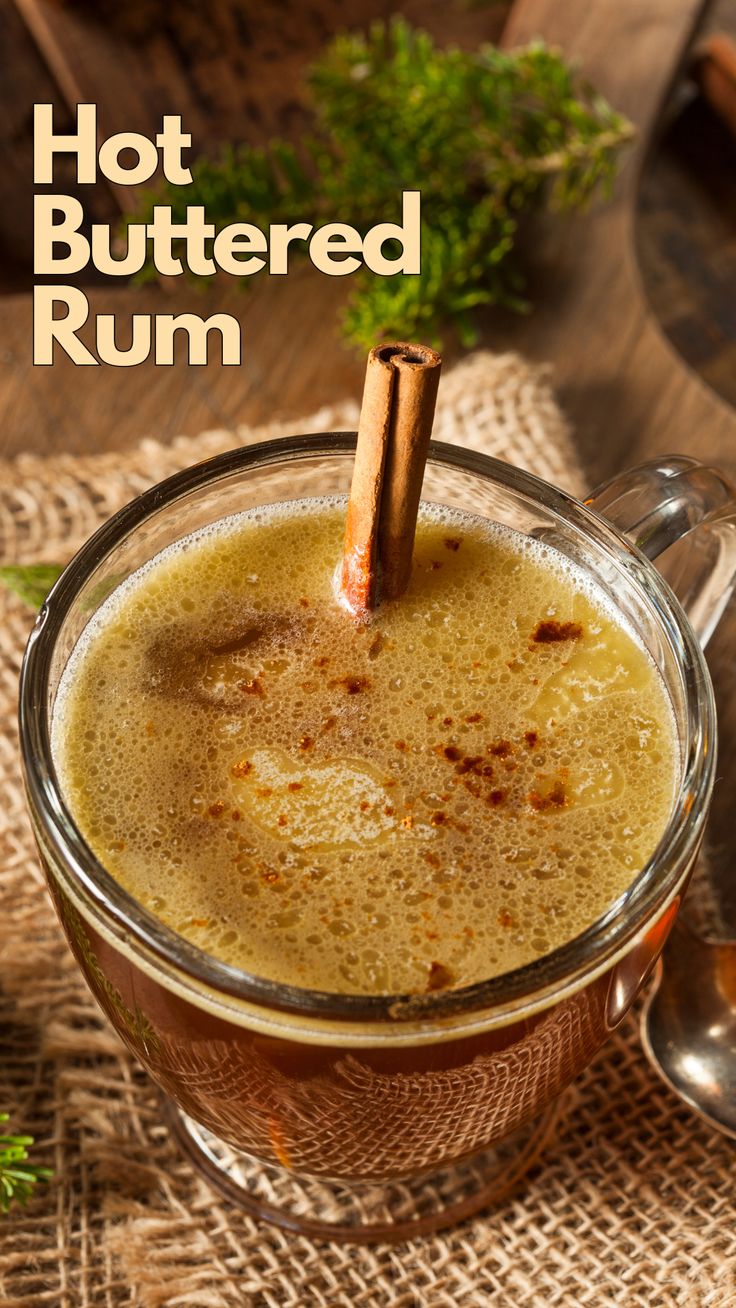 hot buttered rum in a glass mug with cinnamon stick sticking out of it