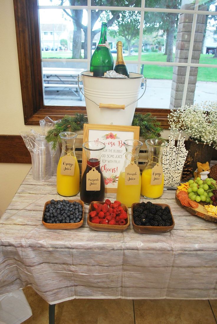 an assortment of fruits and juices on a table in front of a large window