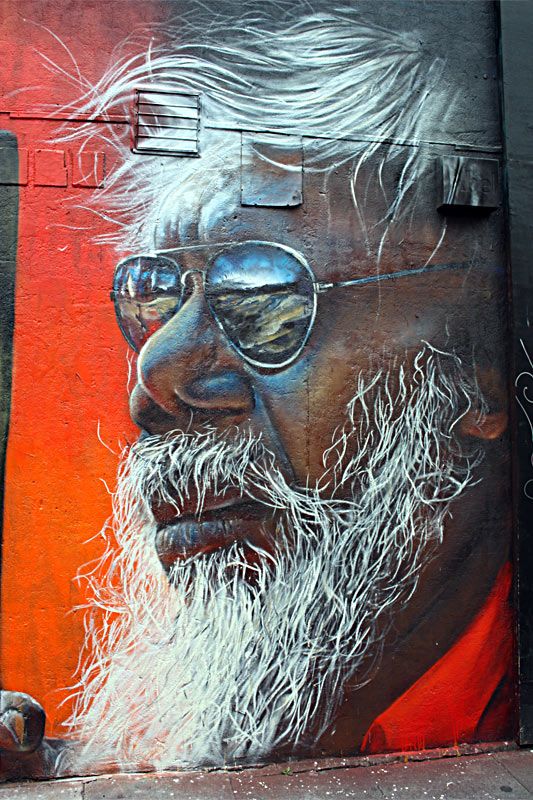 a man with white hair and glasses painted on the side of a building