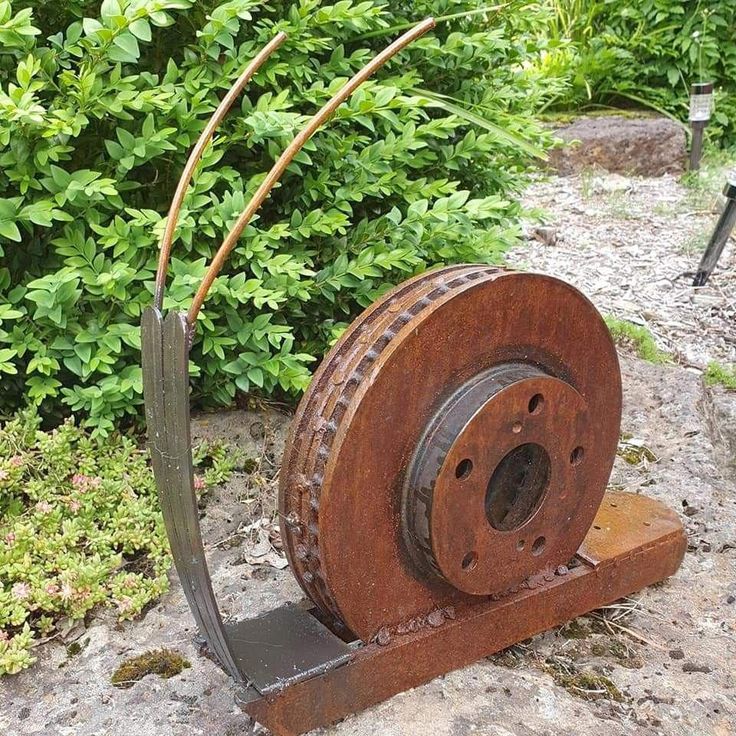 an old metal spool sitting on top of a rock next to some bushes and trees