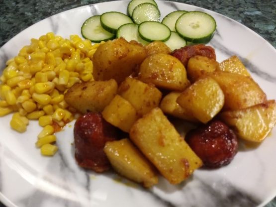 a white plate topped with potatoes, corn and cucumber on top of it